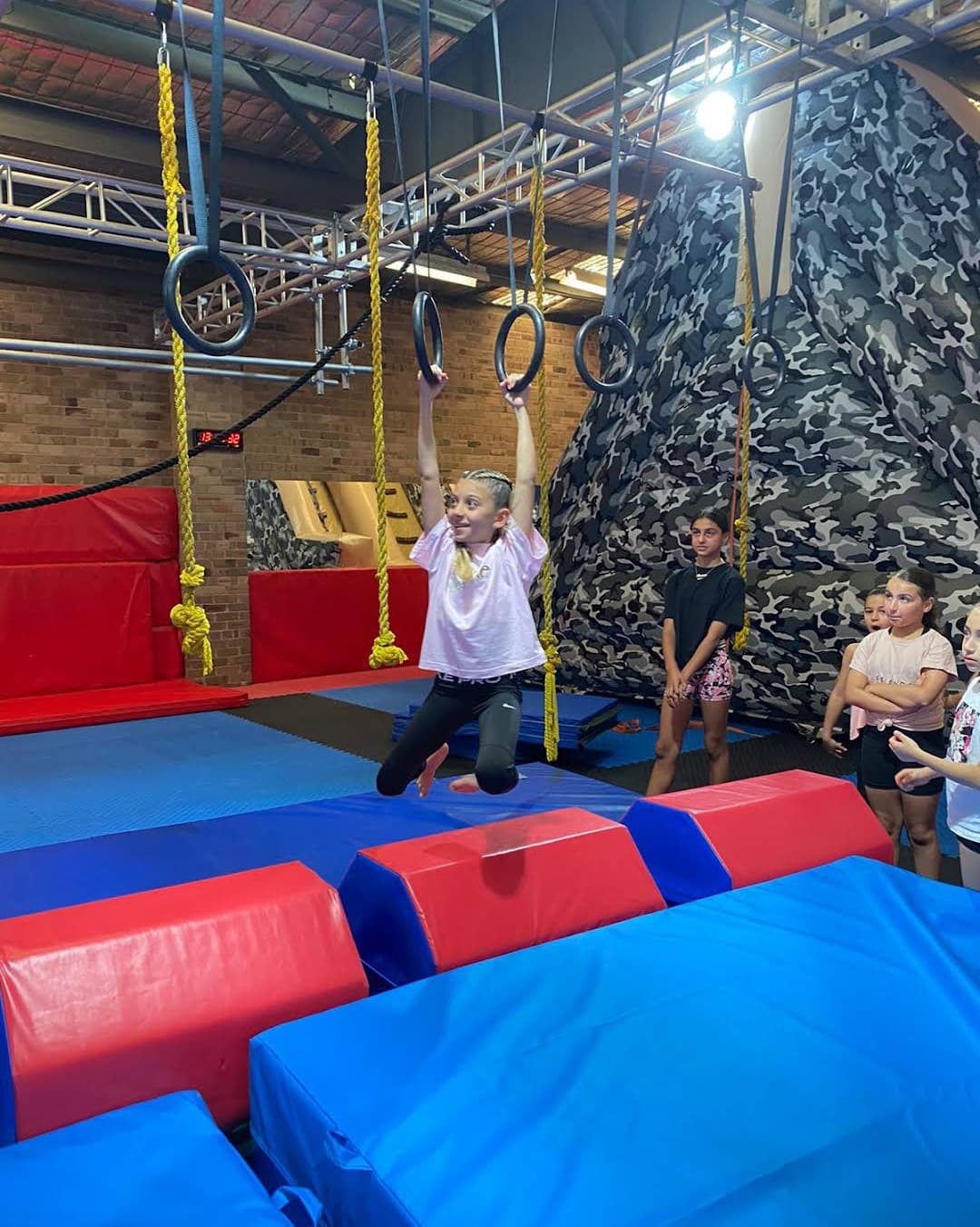 Student working on rings with coaching nearby